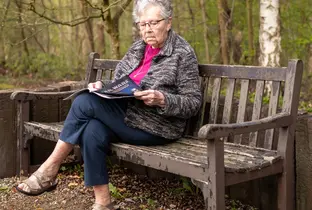 Résidente lisant un magazine sur un banc à la résidence L'Adret