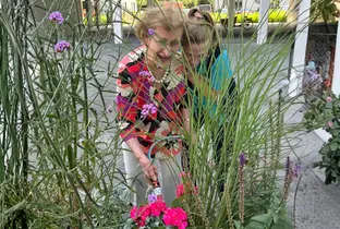Résidente et membre de l'équipe KELA en train de rigoler lors d'une activité jardinage à la résidence Hardoy