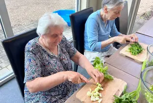 Résident en train de préparer des légumes lors d'un atelier culinaire à la résidence Lucie Lambert
