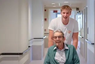 Collaborateur accompagnant un résident dans un couloir de la résidence Pitthem