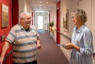 Résident et membre du personnel discutant dans les couloirs de la résidence Pitthem AW