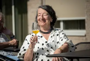 Habitante prenant un apéritif et profitant du soleil à la résidence Pitthem AW