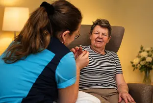 Membre de l'équipe paramédicale réalisant un massage des mains à une résidente à la résidence Pitthem