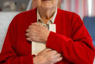 Résident serrant un livre contre lui à la résidence Saint-François dans le cadre du projet Living