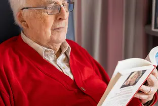 Résident lisant un livre à la résidence Saint-François dans le cadre du projet Living