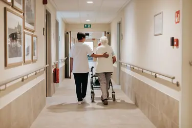 Résidente et infirmière marchant dans un couloir à la résidence De Bottelarij