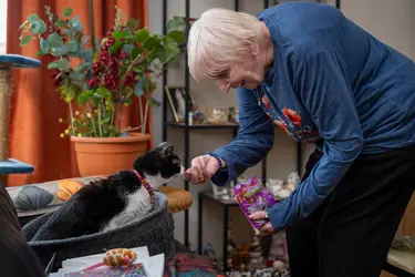 Résidente donnant à mangé à son chat à la résidence Château Chenois dans le cadre du projet Living