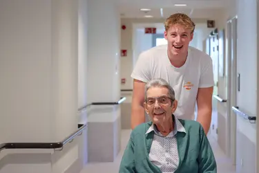 Collaborateur accompagnant un résident dans un couloir de la résidence Pitthem