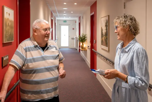 Résident et membre du personnel discutant dans les couloirs de la résidence Pitthem AW